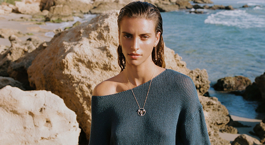 Model wearing ANNOORY gold diamond necklace by the sea