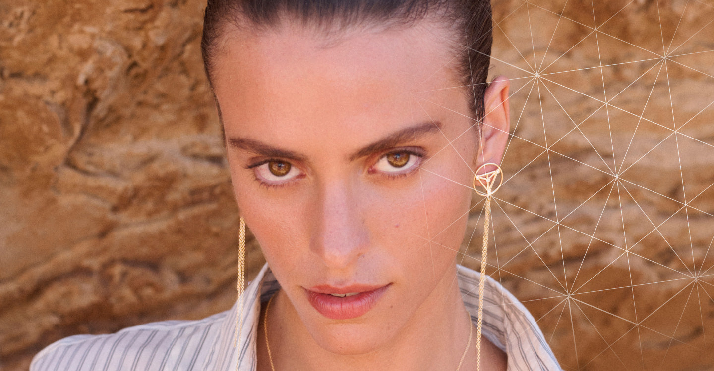 Woman wearing gold earrings with a geometric design in the background
