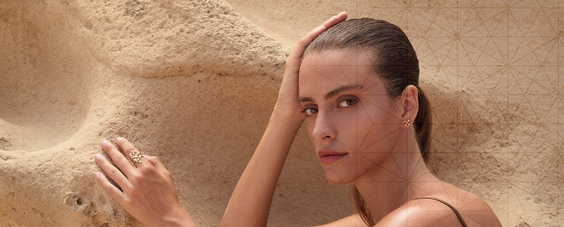 young woman leaning against a rock wearing annoory's jewelry