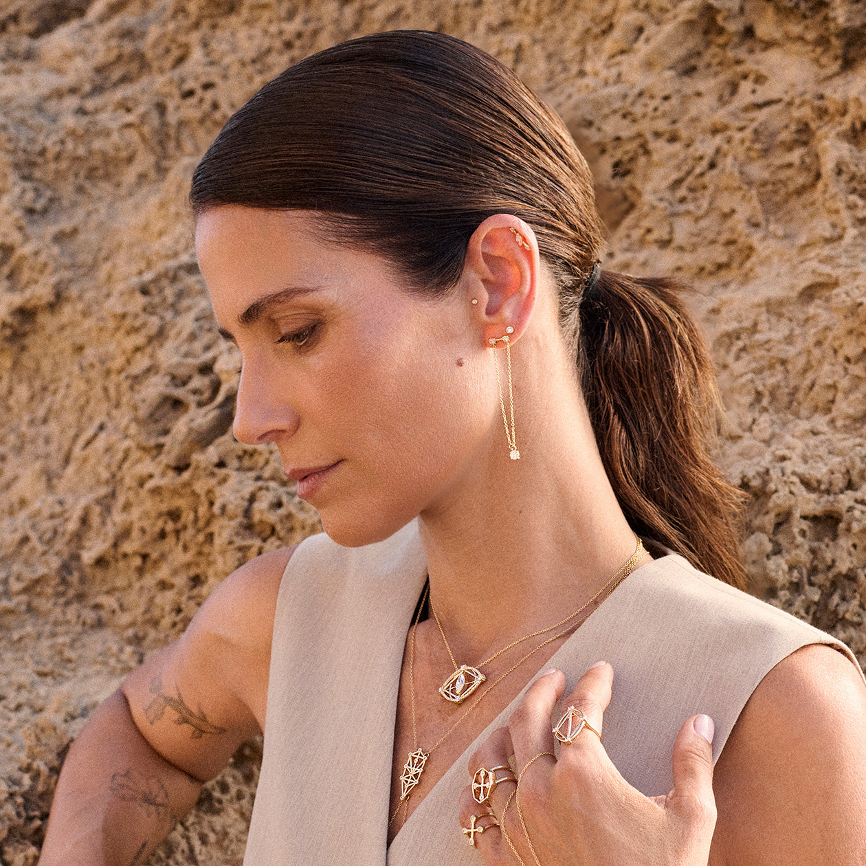 woman wearing sophisticated jewelry leaning against a beige textured background